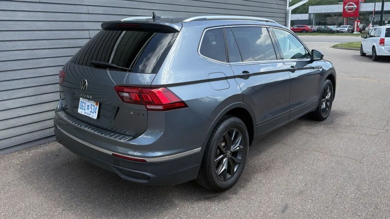 Dark gray SUV parked beside a building in a lot, rear three-quarter view.
