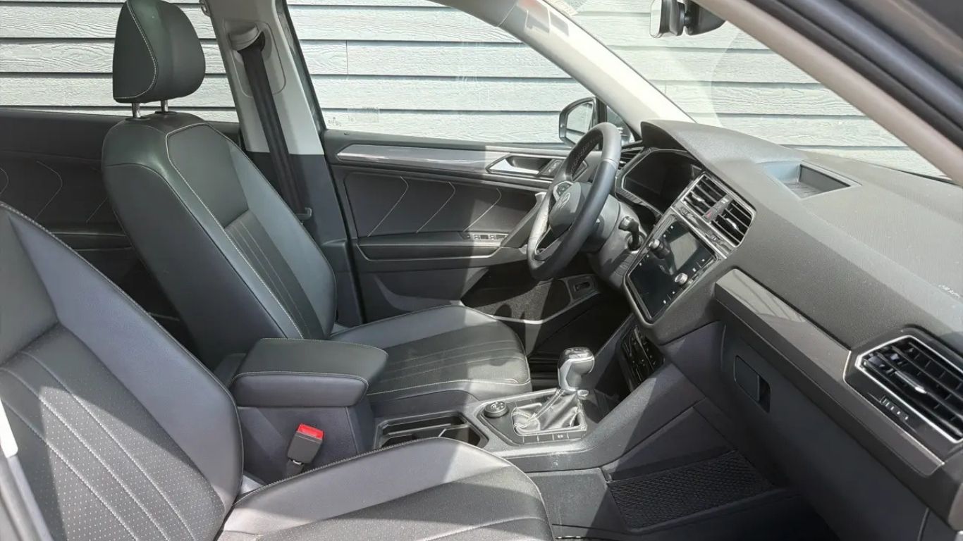 Car interior with black seats, dashboard, center console, and steering wheel in a right-hand drive vehicle