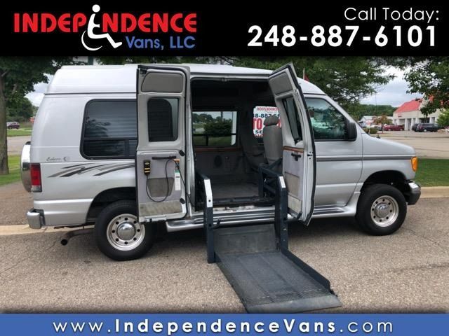 A silver handicap-accessible van with its side doors open and a motorized wheelchair lift deployed to the ground.