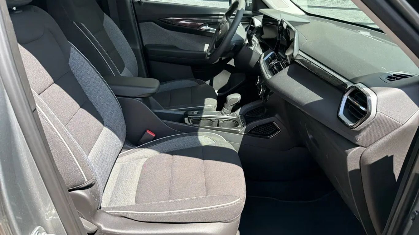 Front interior of a car with gray fabric seats, steering wheel, and center console visible.