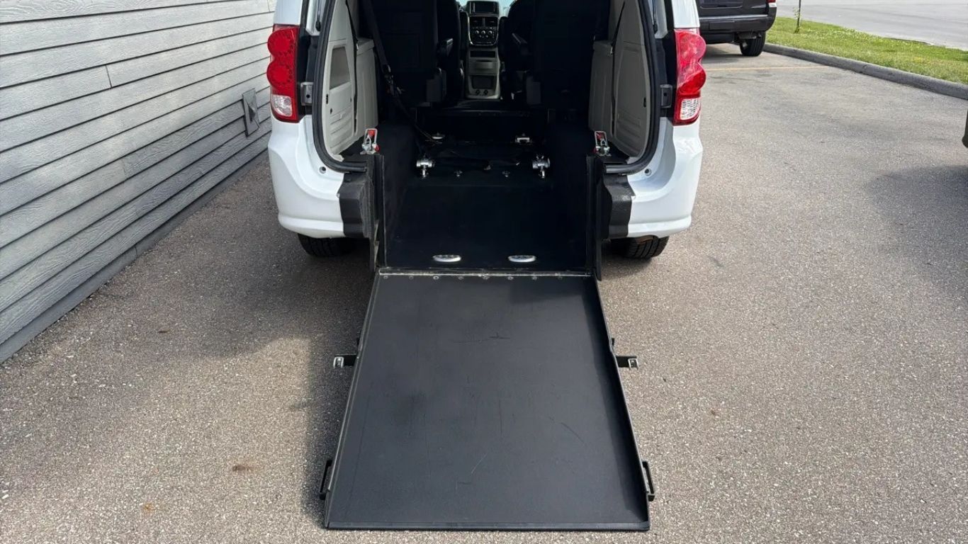 Rear view of a white van with its cargo ramp lowered onto pavement