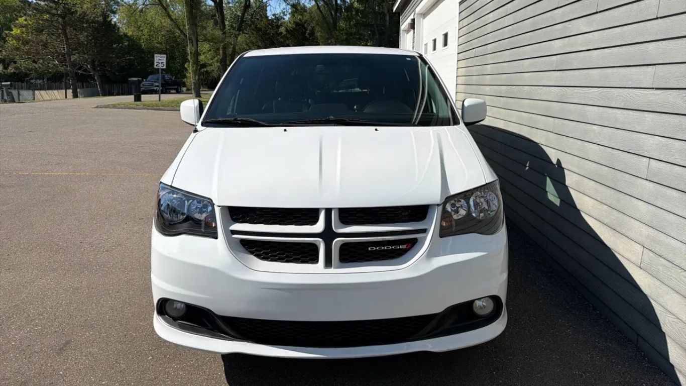 White Dodge SUV parked beside a building in a sunny outdoor lot.