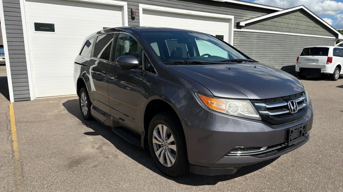 Gray Honda minivan parked in front of a garage on a sunny driveway.