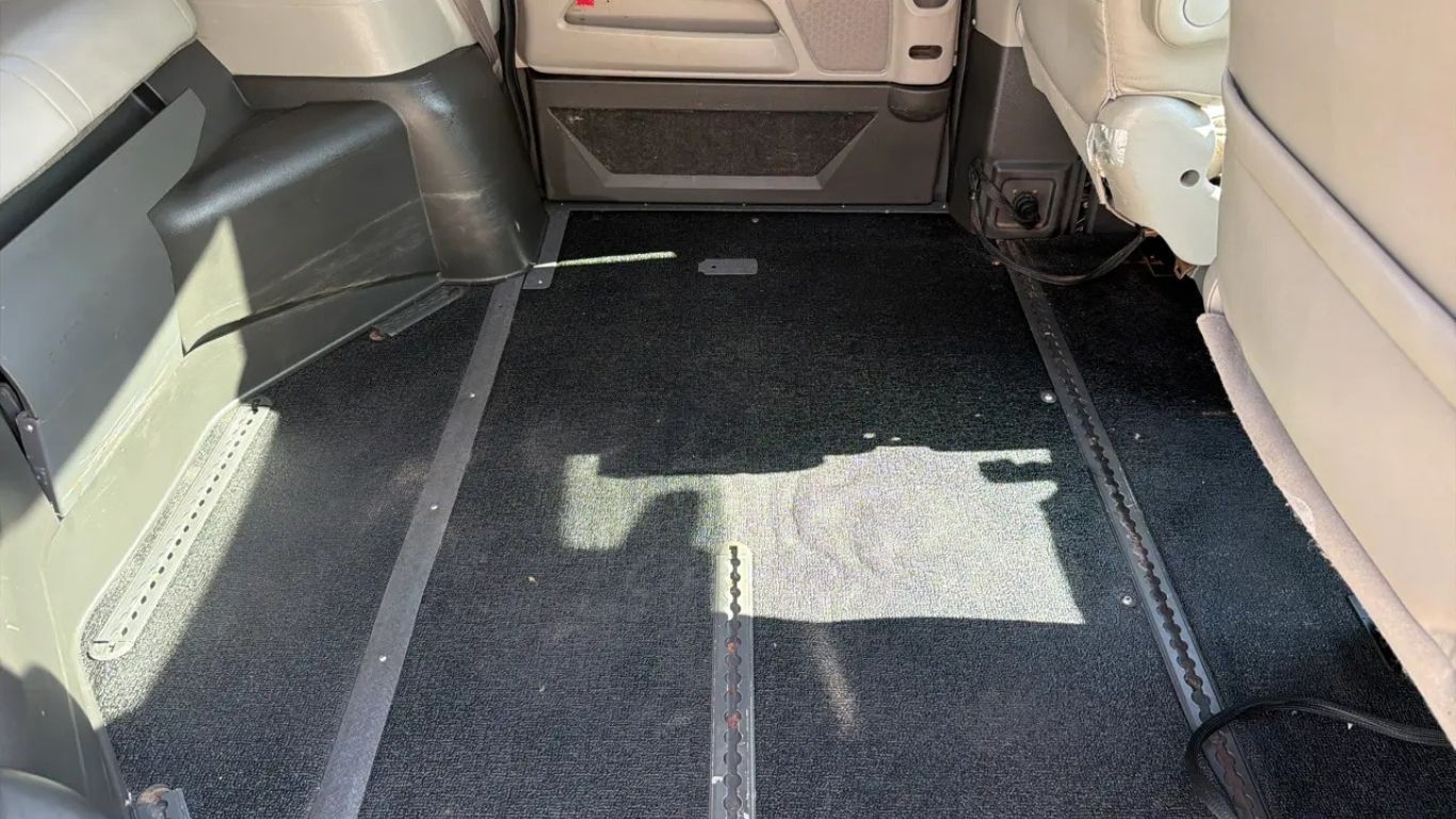 Empty vehicle cargo area with black carpeted floor and beige interior panels