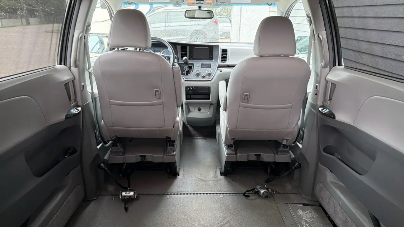 Interior of a van with two gray front seats and an empty cargo area with folded floor panels.
