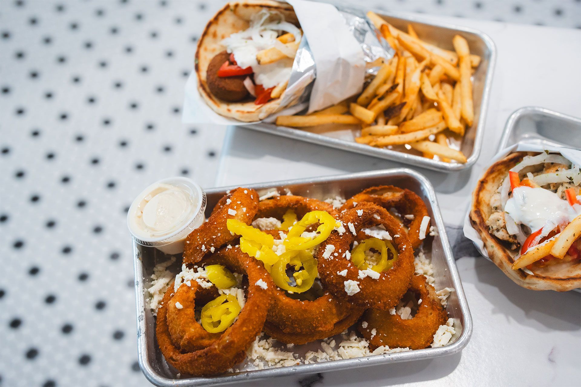 A table topped with plates of food including onion rings and french fries