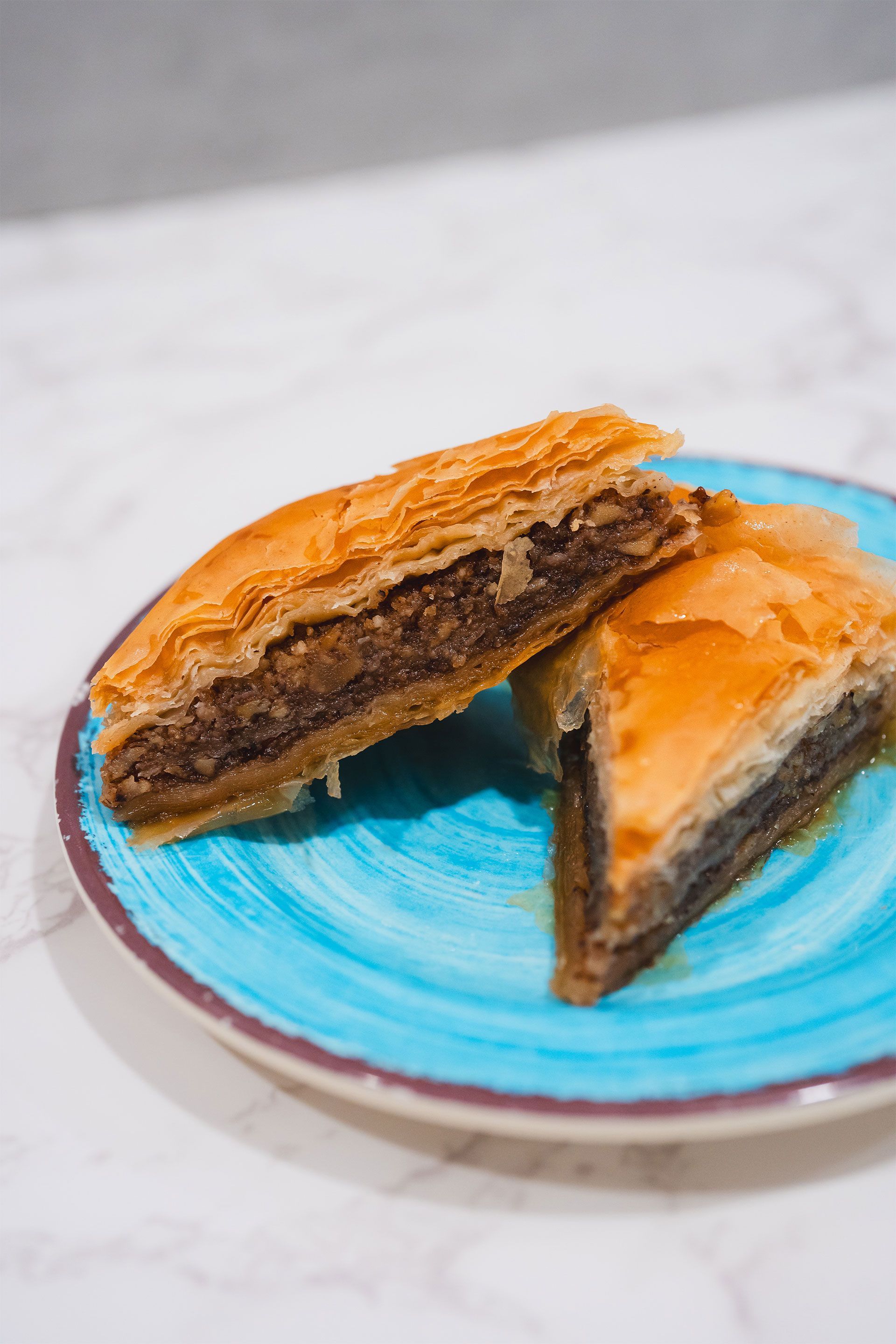 Two slices of baklava on a blue plate on a table
