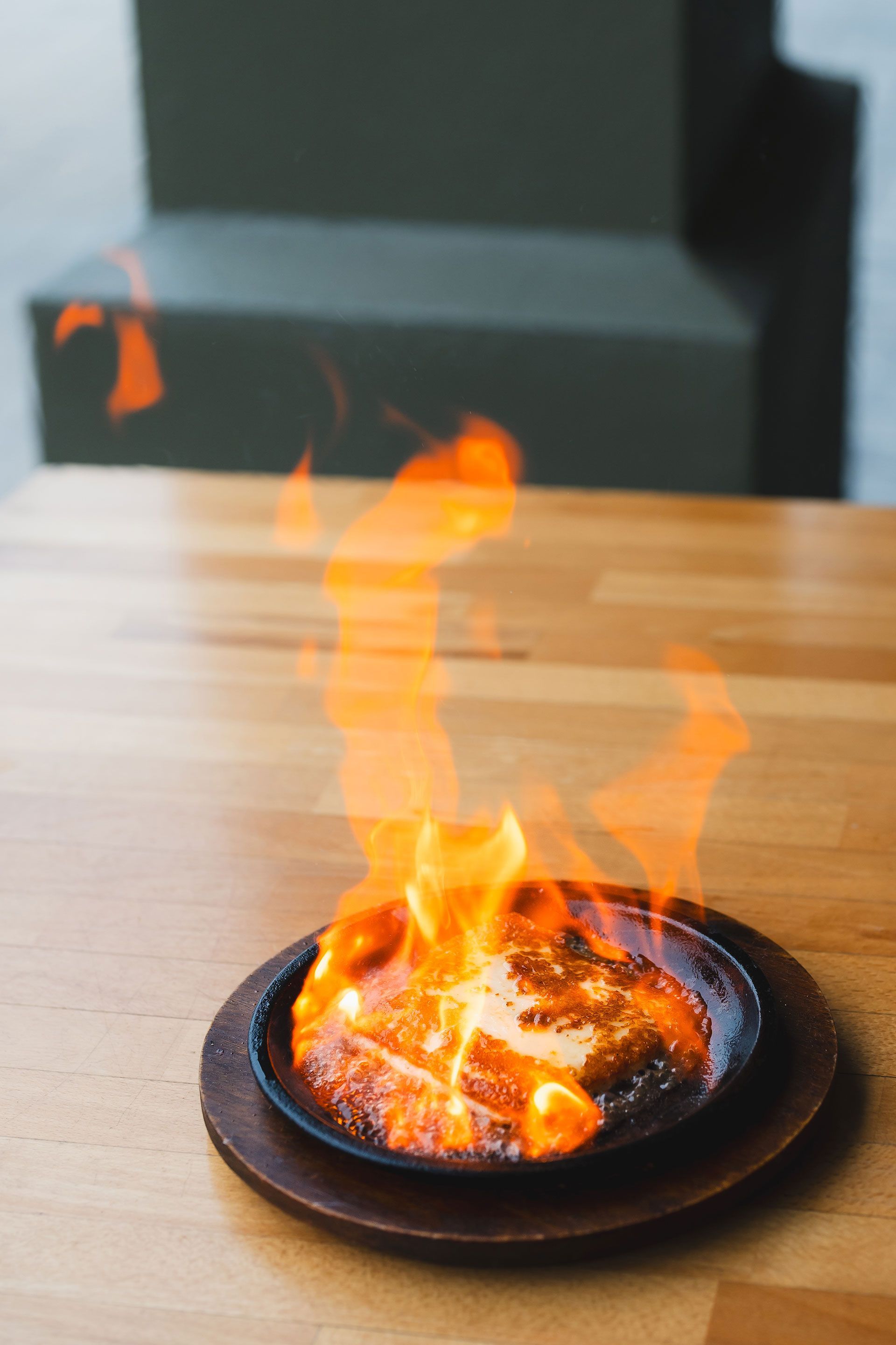 A plate of food with flames coming out of it on a wooden table