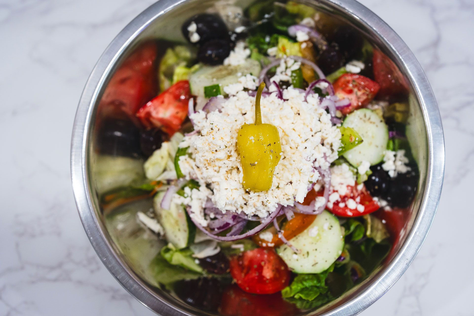A close up of a salad in a metal bowl on a table