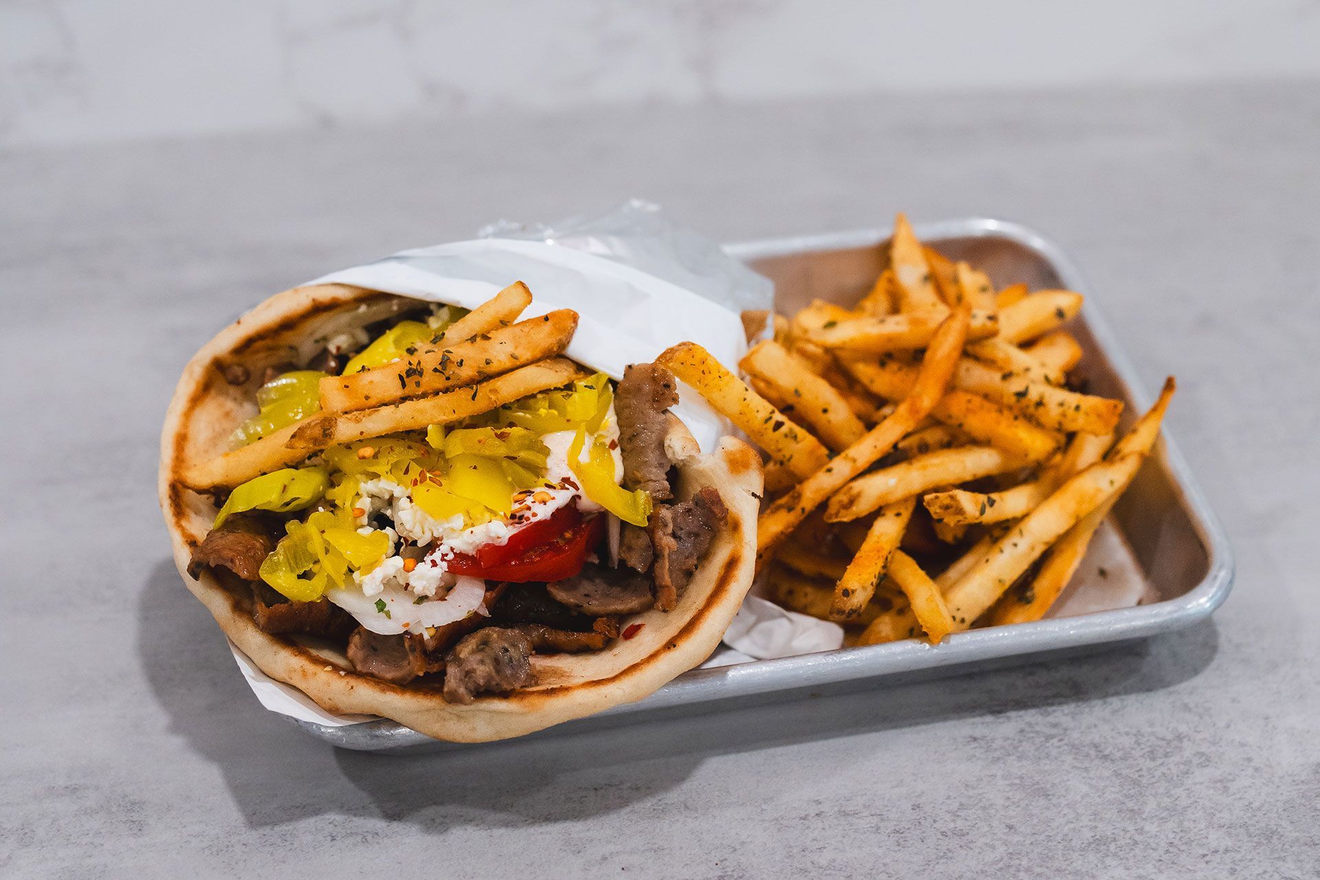A gyro sandwich and french fries on a tray on a table