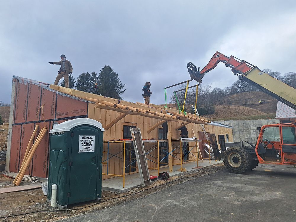 Construction site: workers building a wooden structure, a forklift, and a portable toilet.
