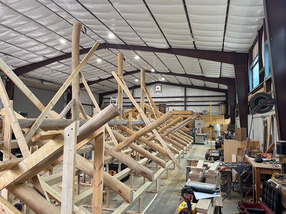 Workshop interior: Wooden beams and supports being assembled under a white ceiling.