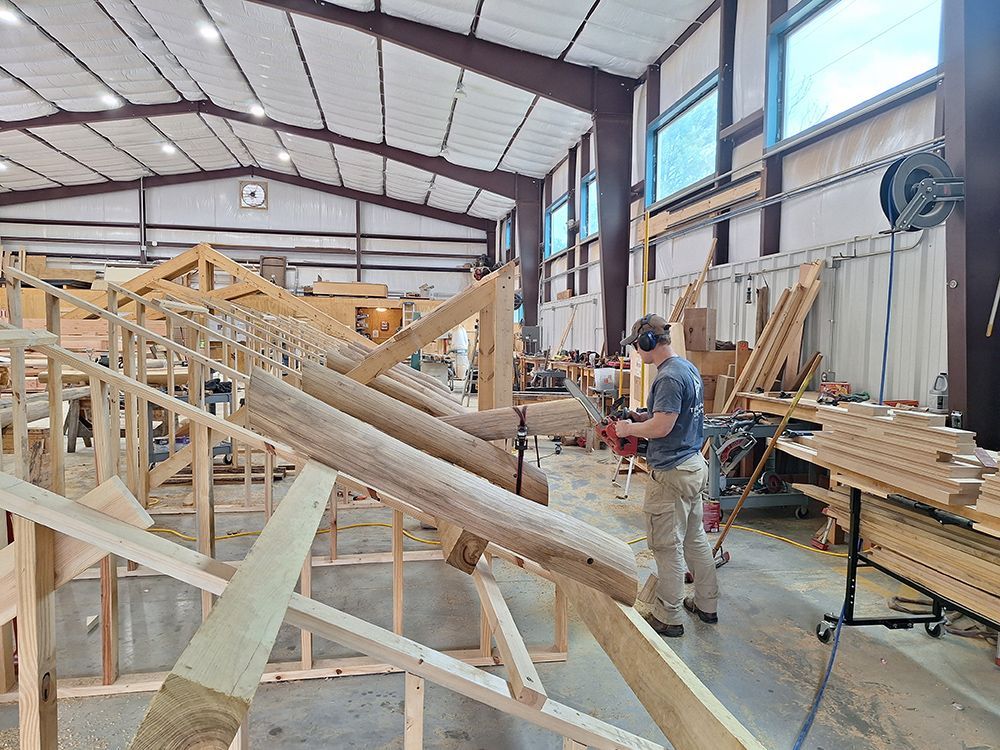 A person cutting wood with a power saw in a workshop with wood framework.