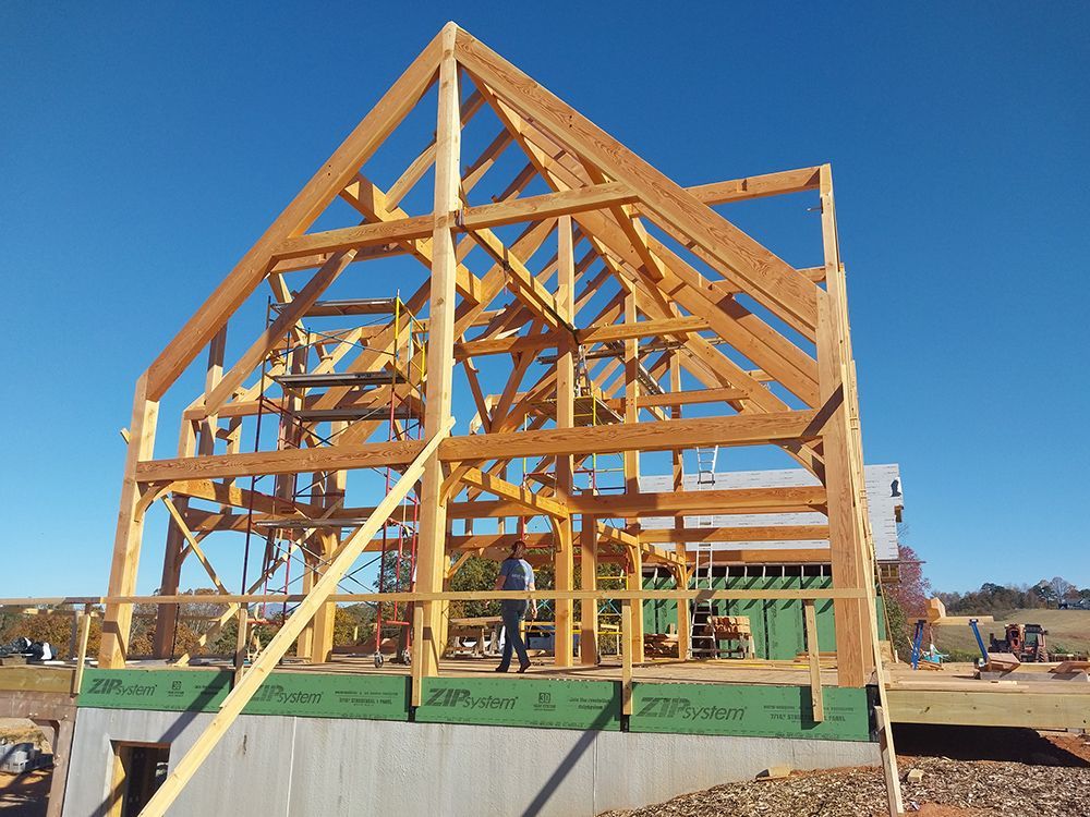 Wooden frame of a house under construction; clear blue sky.
