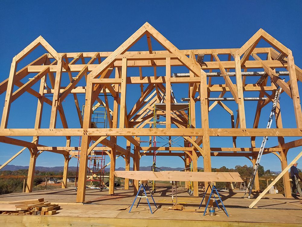 Wooden frame of a house under construction against a clear blue sky.