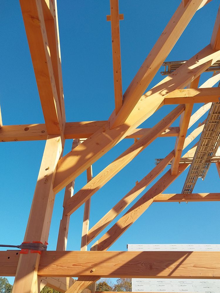 Wooden roof frame construction against a bright blue sky.