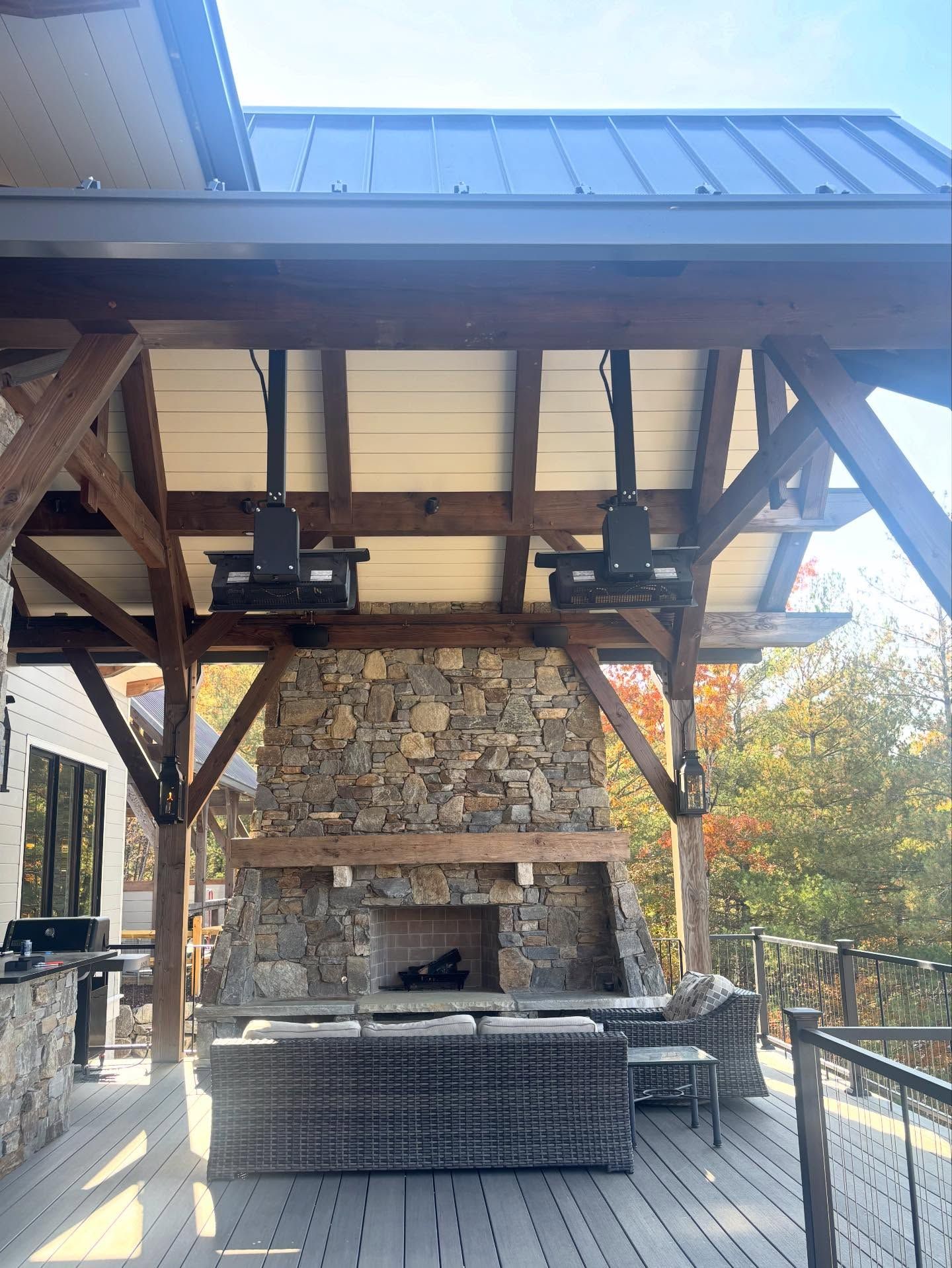 Outdoor patio with stone fireplace, wood beams, and mounted heaters.