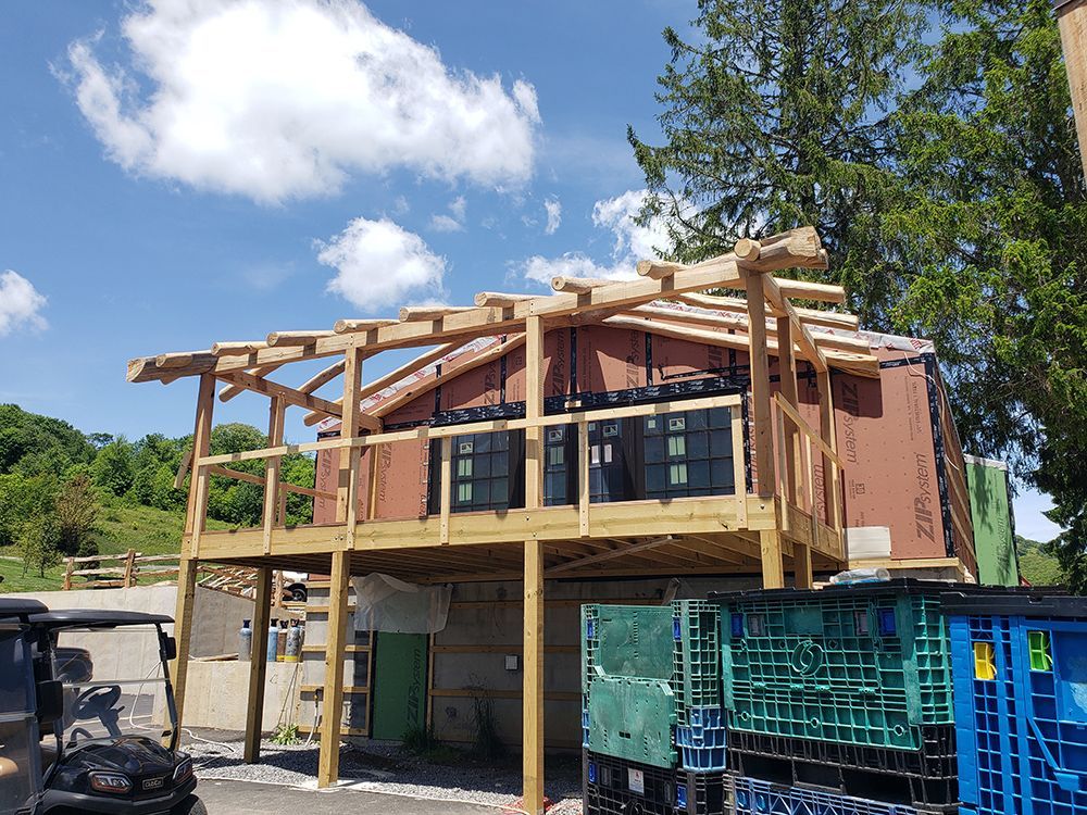 Building under construction with wooden deck and open roof, blue sky background.