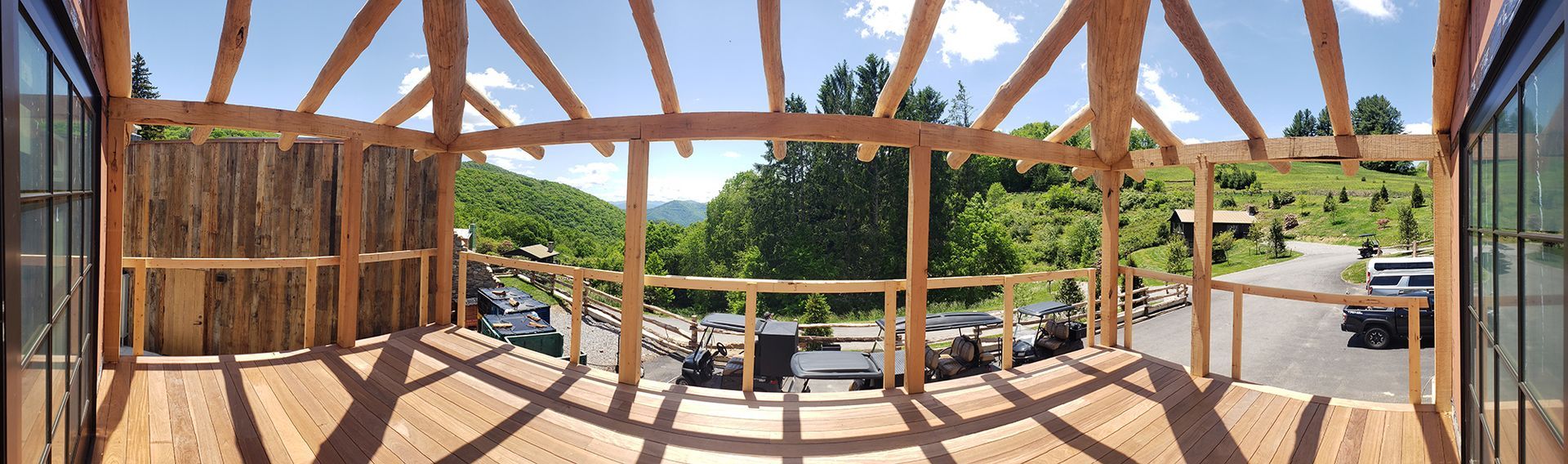 Wooden framed building with a view of a lush green landscape and parked cars.
