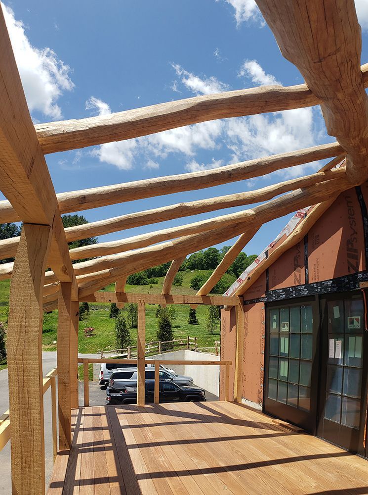 Wooden deck with log beams, blue sky and cars in the distance.