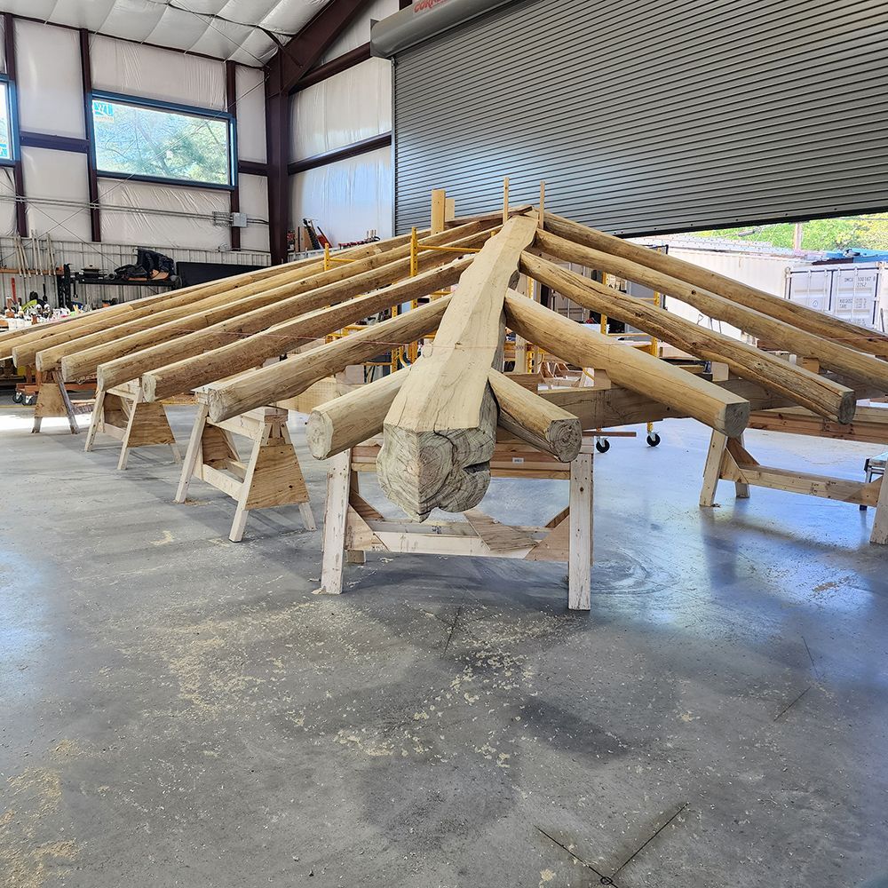 Wooden roof structure under construction inside a workshop, supported by sawhorses.