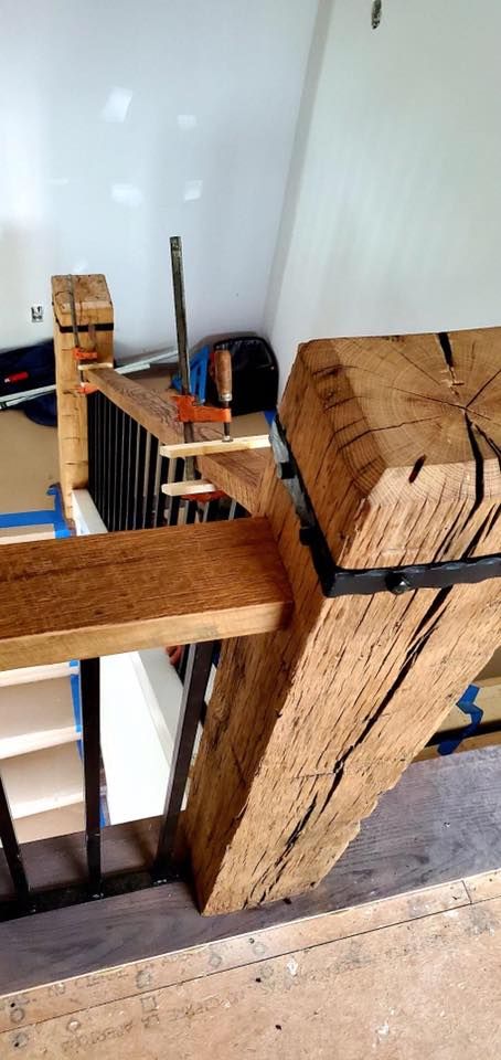 Wooden staircase with black metal railing and large wooden post.
