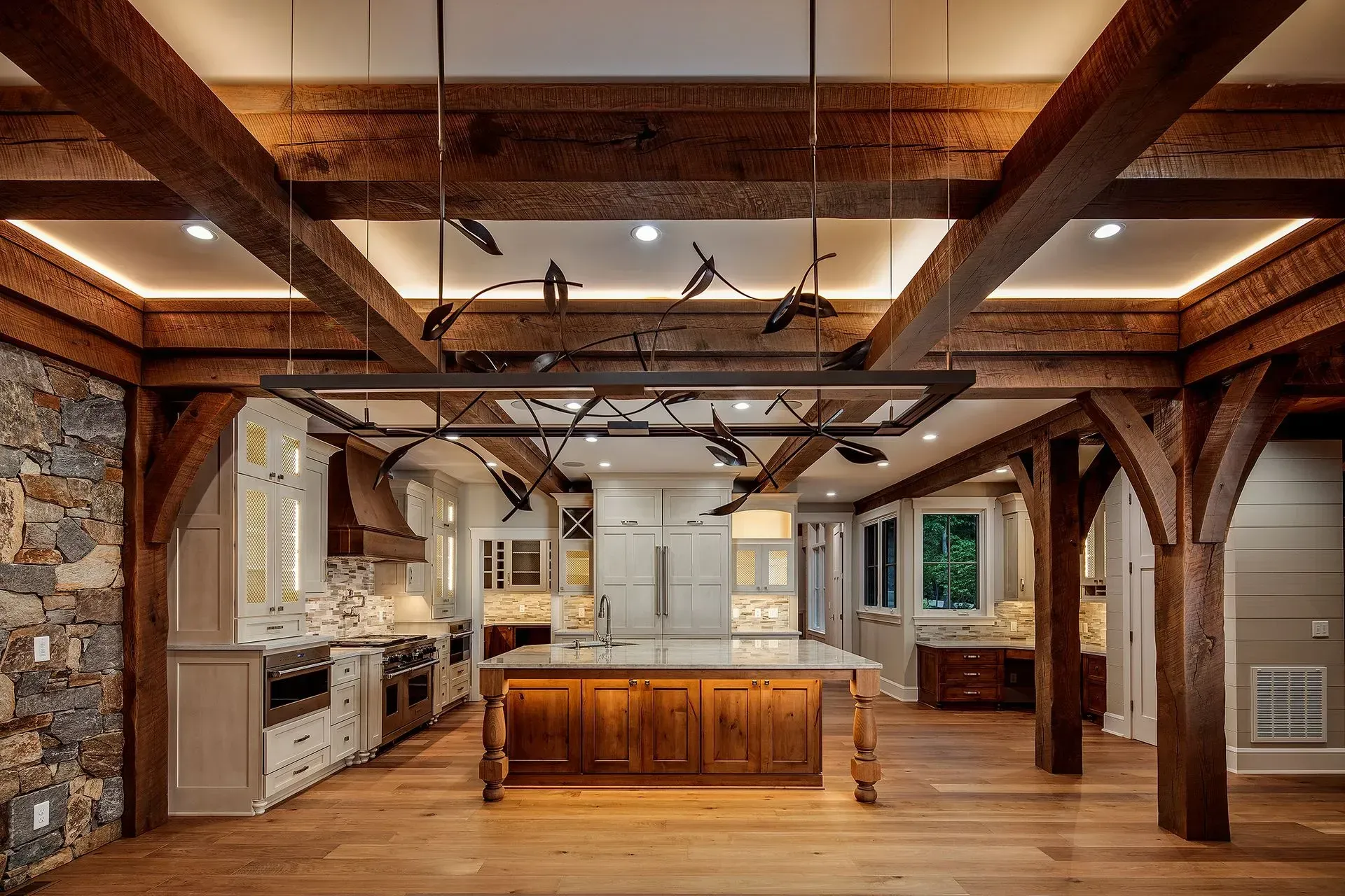 Rustic kitchen with wood beams, stone wall, and central island.