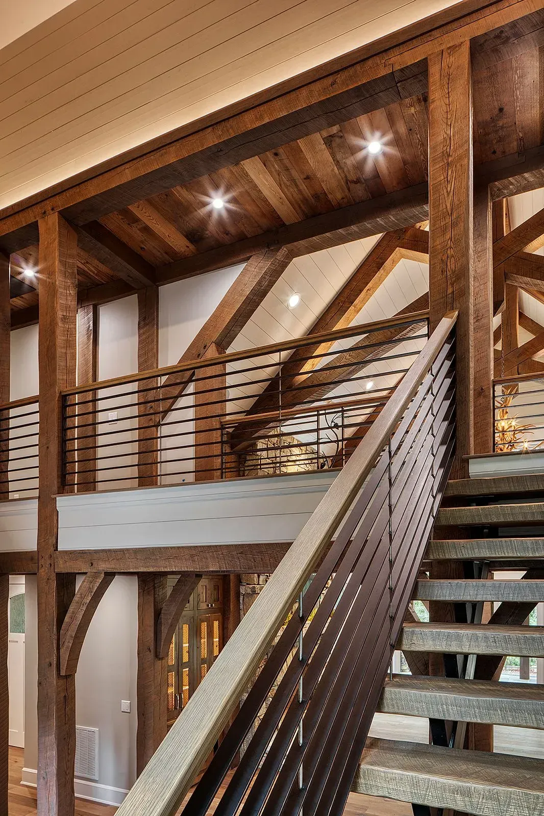 Wooden staircase with dark metal handrails and exposed beam architecture.