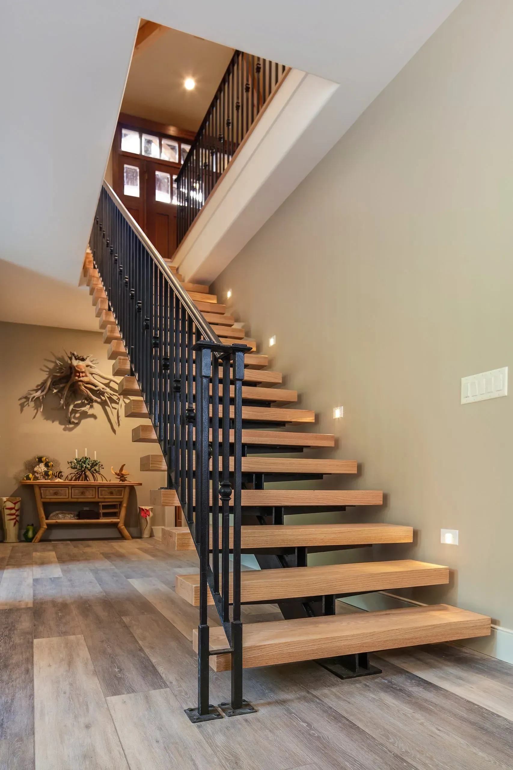 Wooden staircase with black metal railing. Light wood floors, tan walls.