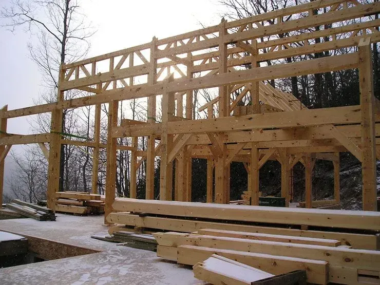 Wooden timber frame of a building under construction, outdoors with snow.