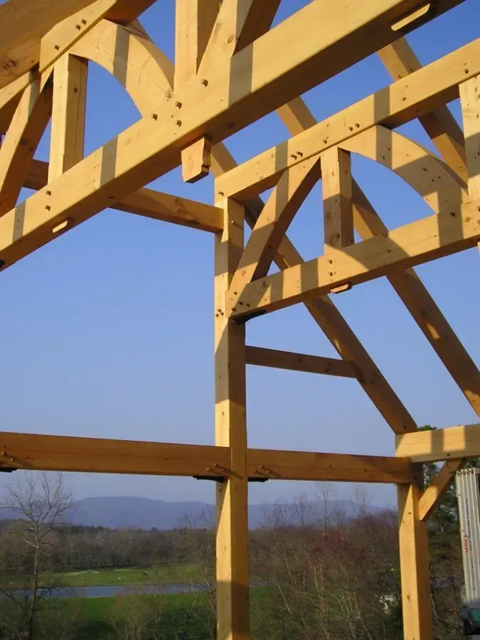 Wooden timber frame construction against a blue sky, with mountain view in the background.