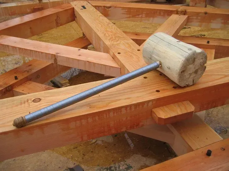 Wooden mallet and steel rod resting on a wooden framework, likely for construction.
