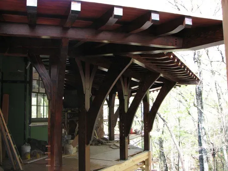 Wooden porch under construction with curved beams and supports.