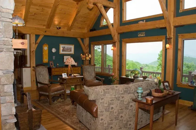 Living room with wood beams, blue walls, and a view of mountains.