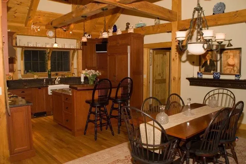 Kitchen and dining area with wooden beams, cabinets, and furniture.