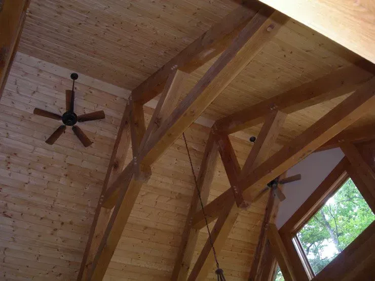 Wooden vaulted ceiling with exposed beams, a ceiling fan, and a window.