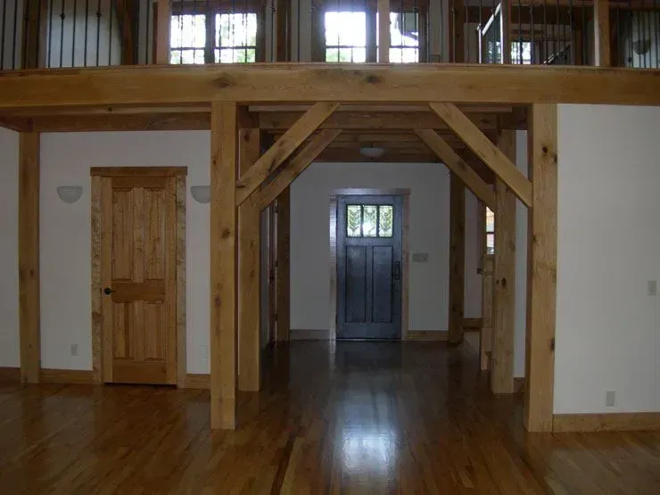Wooden-framed interior, hardwood floors, a door on the left, and a front door at the end of the hall.