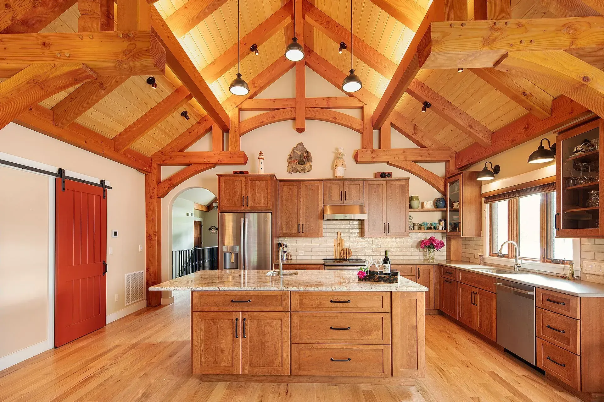 Spacious kitchen with wood beams, island, cabinets, and a red sliding door.