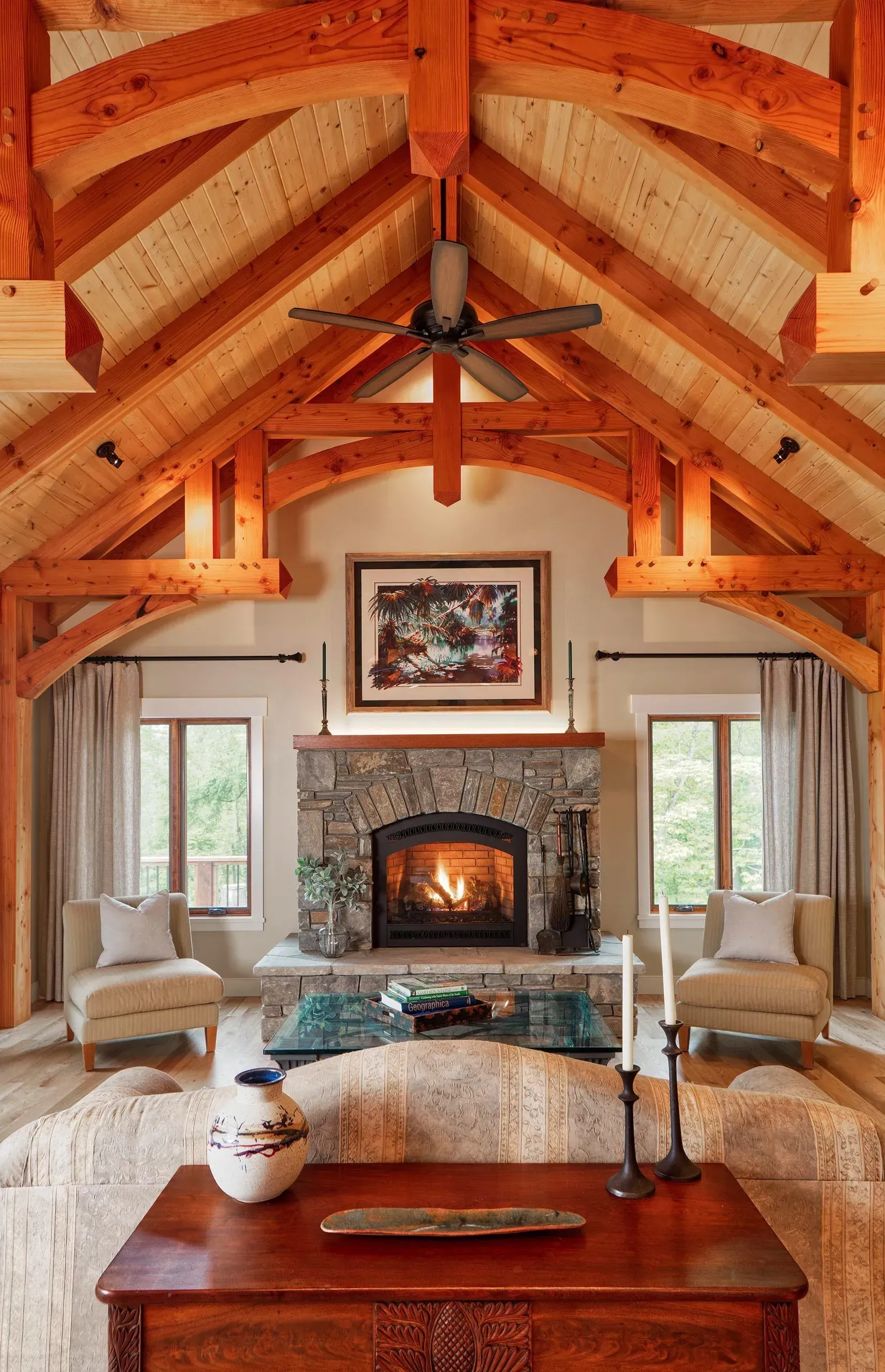 Living room with exposed wood beams, stone fireplace, and two armchairs.