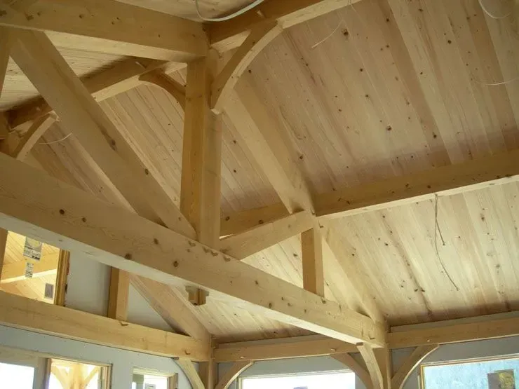 Wooden timber frame ceiling with rafters and beams. Light wood tones.