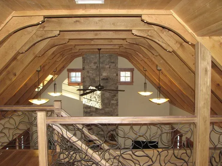 Interior view of a wooden loft with a stone chimney and decorative iron railing.
