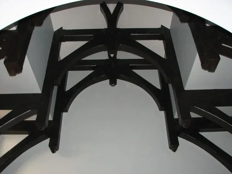 Dark wood archway and structural supports against a white ceiling.