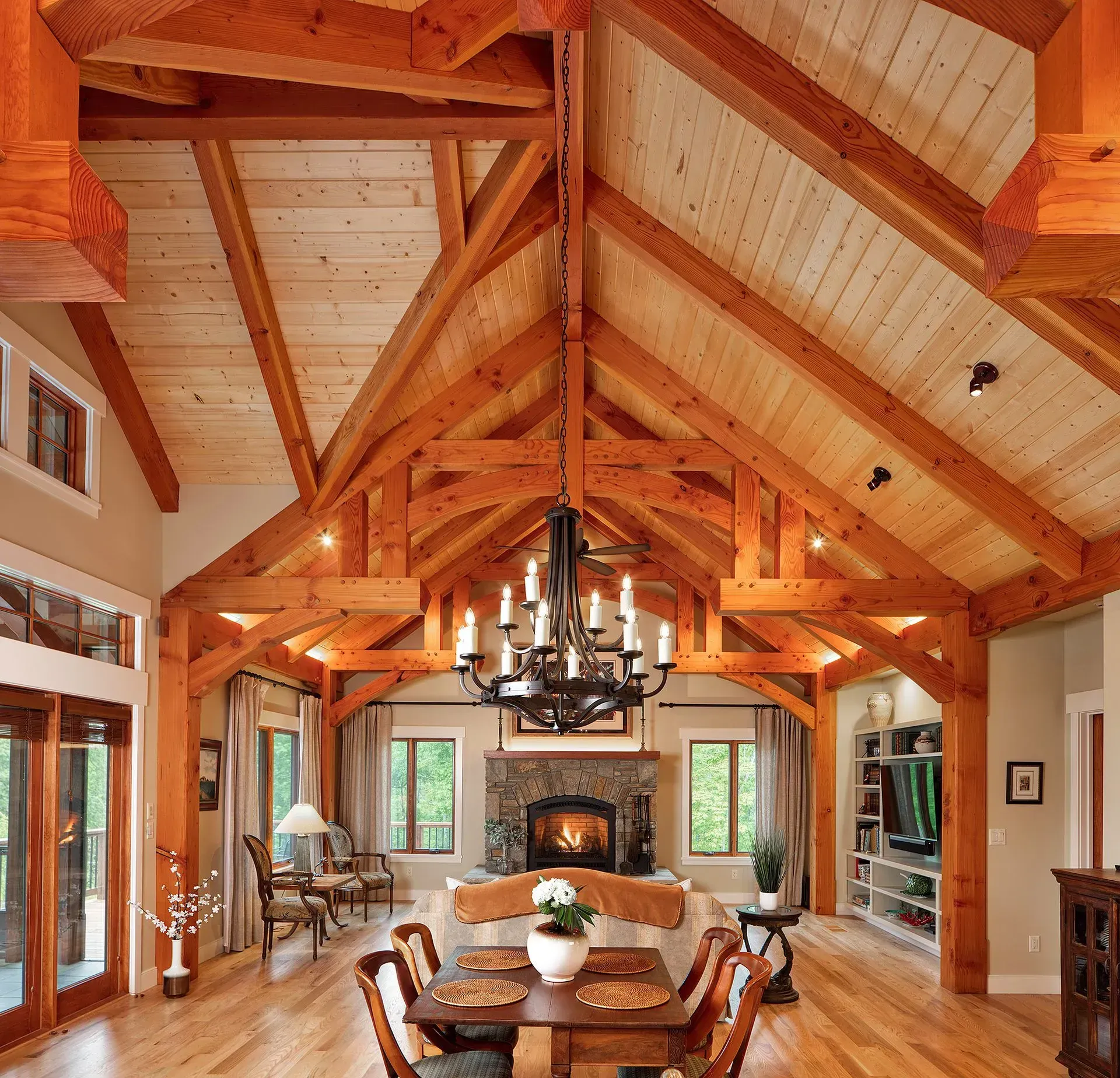 Wooden-beamed dining room with chandelier, fireplace, and light wood flooring.