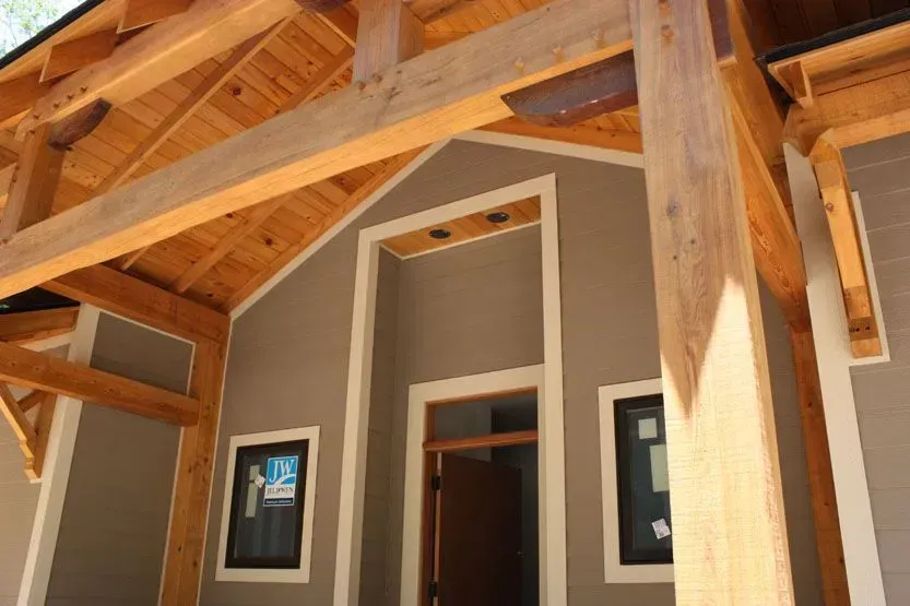 Entrance with brown wooden beams, gray walls, and a wooden door.