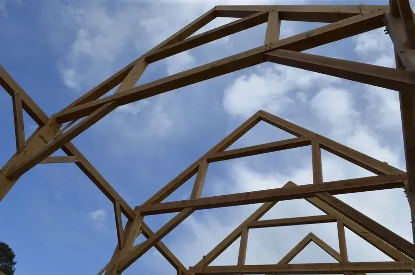 Wooden beams forming the frame of a building against a cloudy blue sky.