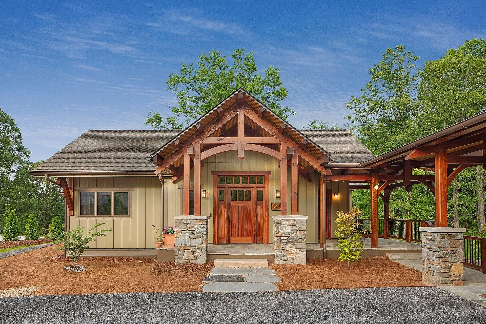 Cabin with wooden door and stone accents, surrounded by trees under a blue sky.