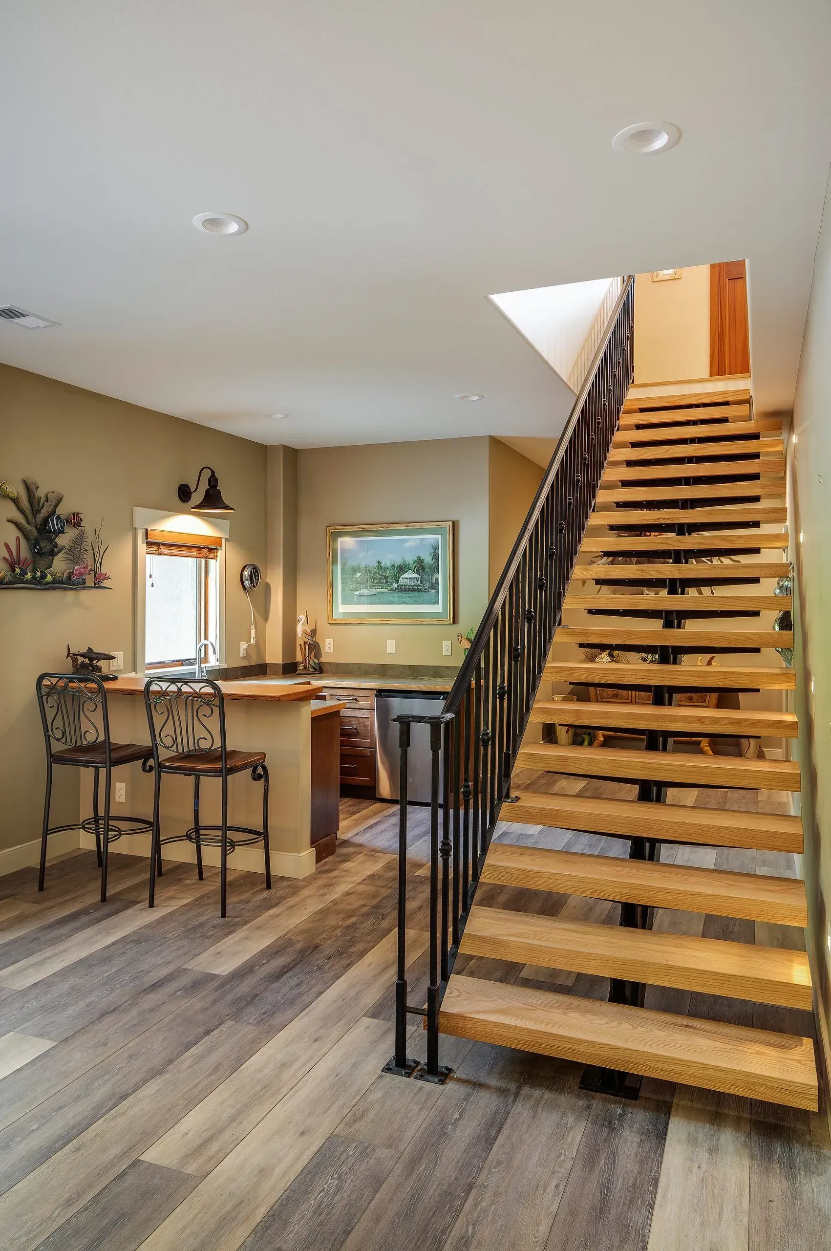 Wooden staircase with black railing leads to a doorway. A small bar with stools is on the left.