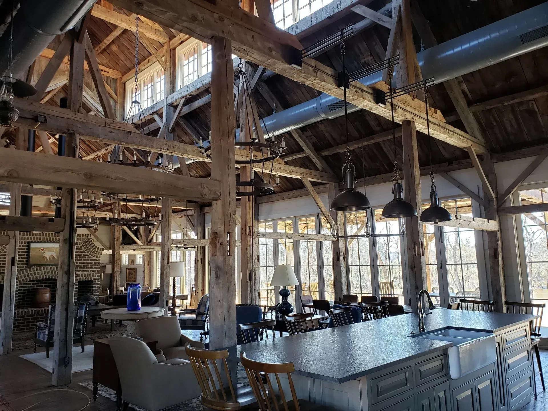 Spacious rustic interior with wooden beams, large windows, and an island counter.