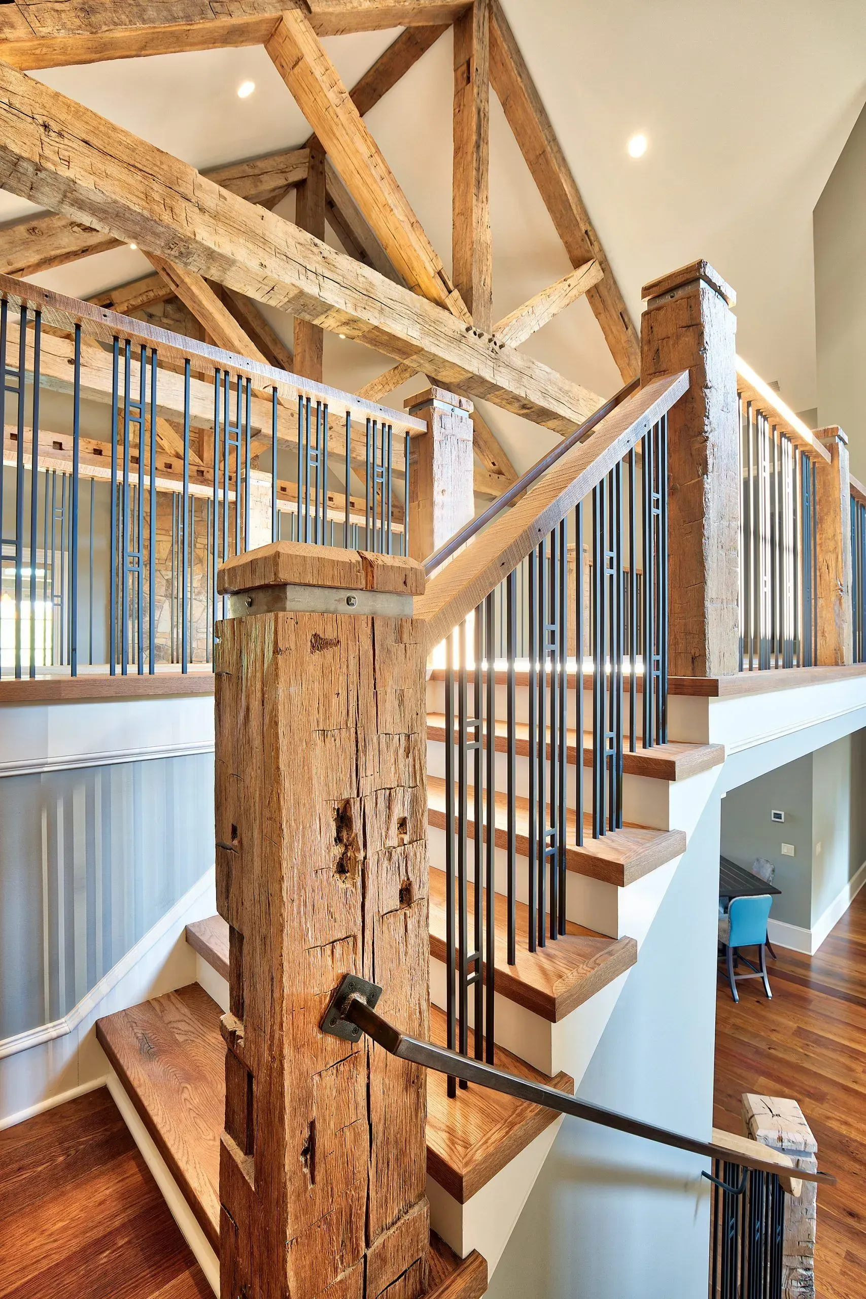Rustic wooden staircase with black metal railings, leading to a loft.
