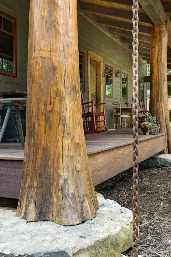 Wooden porch with large log pillars and a rusty chain hanging down.